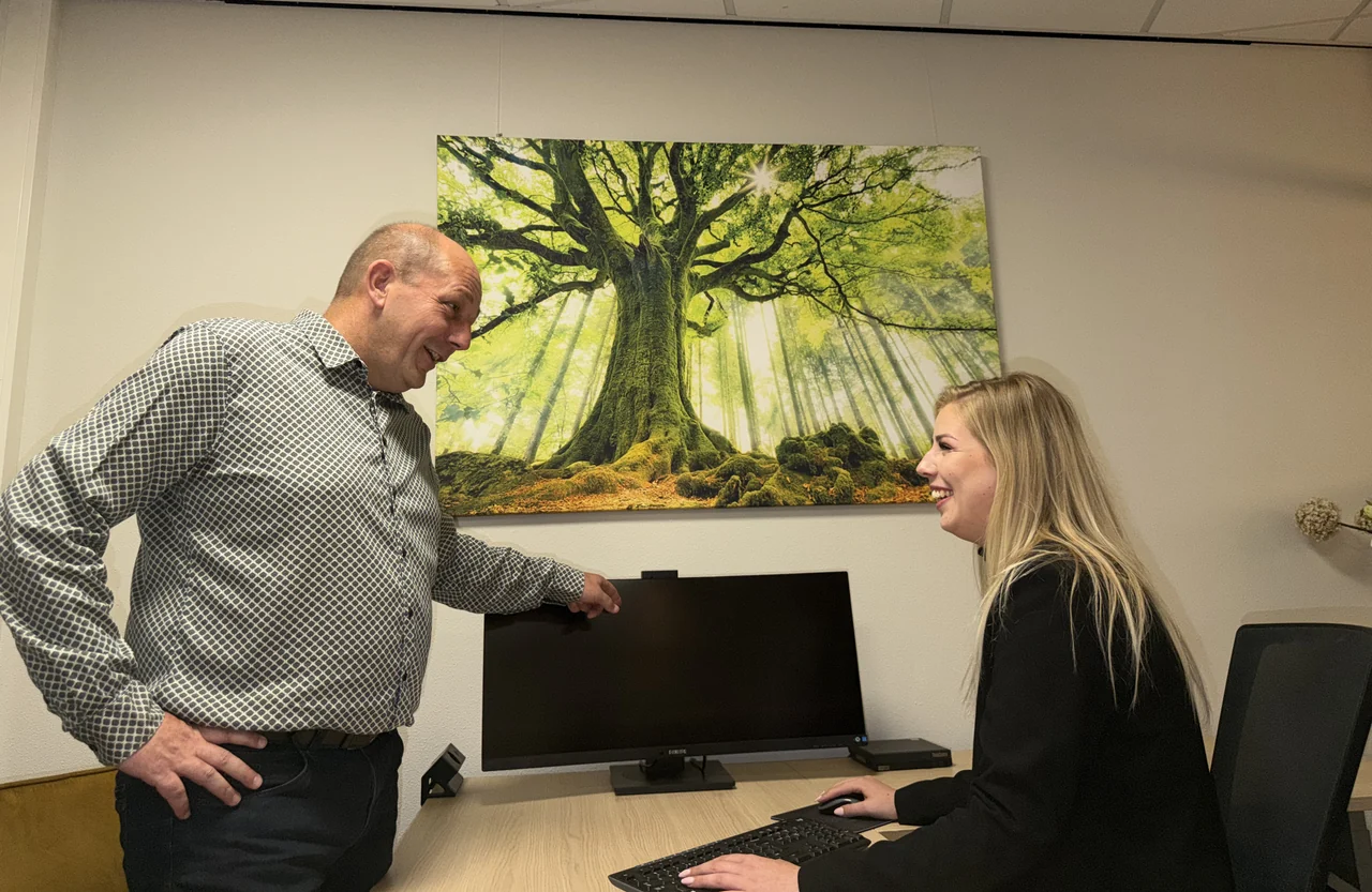 Twee teamleden overleggen bij een werkplek op kantoor